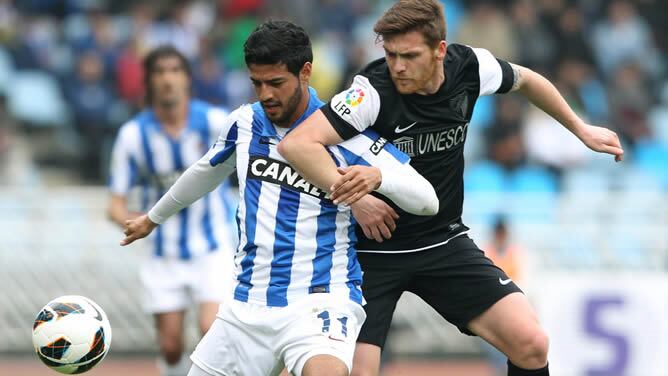 El delantero de la Real Sociedad Carlos Vela (i), y el defensa del Málaga Vitorino Antunes, luchan por el balón durante el partido correspondiente a la trigésima jornada de Liga que disputan en el estadio de Anoeta de San Sebastián