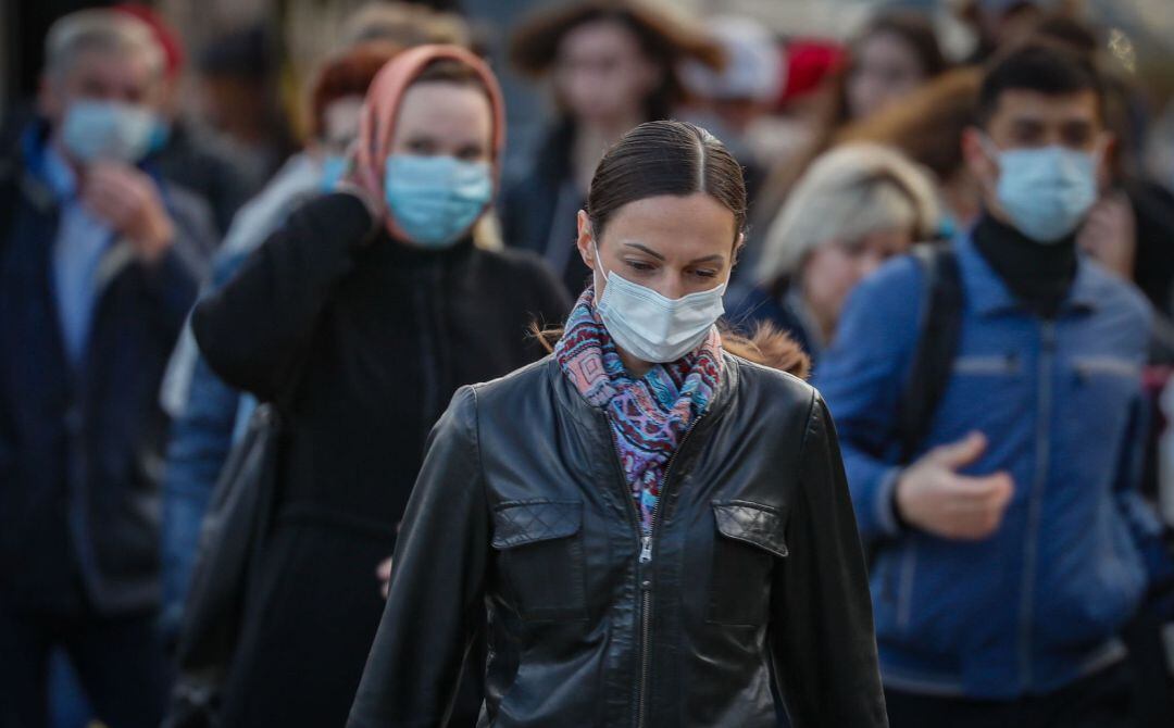 Varias personas caminan con mascarillas.