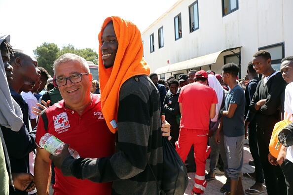 Un migrante abraza a un miembro de la Cruz Roja en el centro de acogida de Lampedusa (Italia)