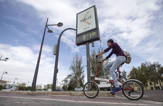 Un ciclista pasa ante un termómetro en la ciudad de Valencia que marca 31 grados. El alto porcentaje de humedad y el viento de poniente han hecho subir el mercurio considerablemente en pleno otoño.