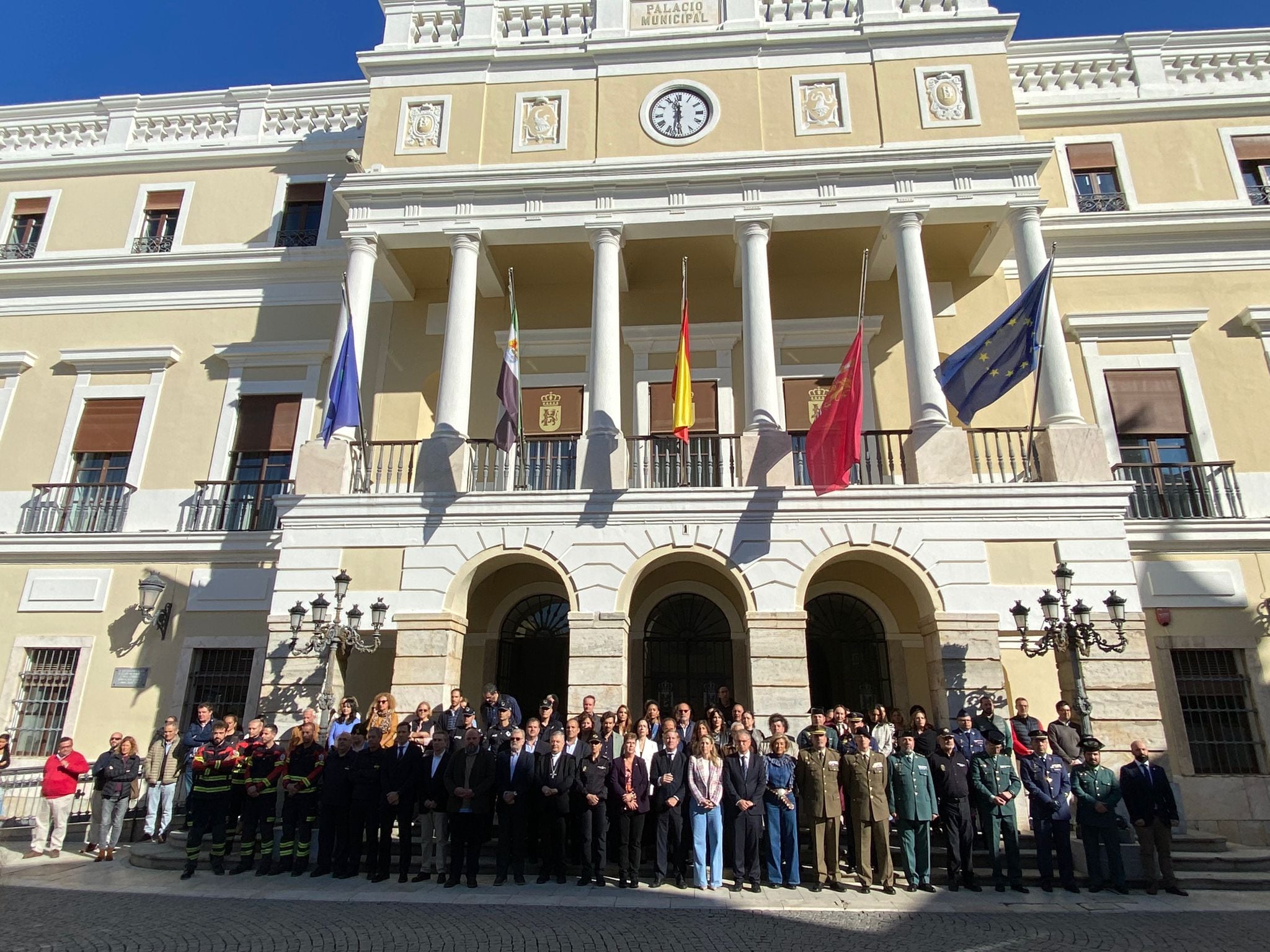 Autoridades guardando cinco minutos de silencio a las puertas del Ayuntamiento de Badajoz por las víctimas de la riada de 1997 y las de Valencia