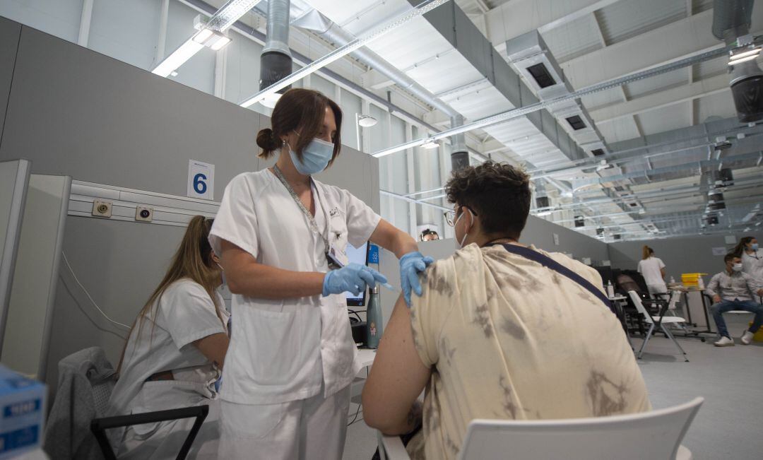 Una enfermera vacunando a un joven en el Hospital Isabel Zendal de Madrid.