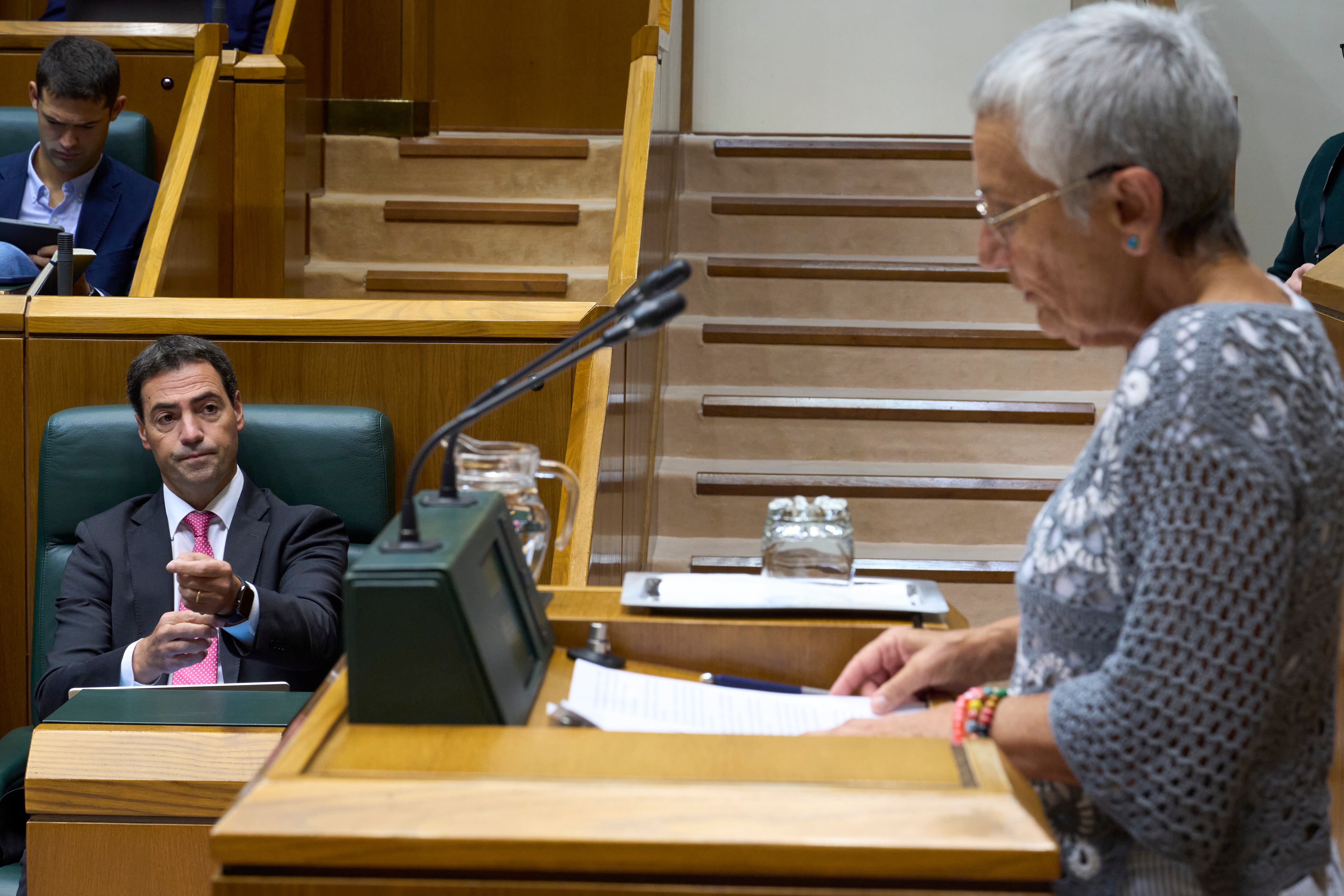 VITORIA, 25/09/2025.- La portavoz de los pensionistas Ana Mezo (d) es observada por el lehendakari Imanol Pradales (i), este jueves en el pleno del PArlamento Vasco que debate la proposición de iniciativa popular de las asociaciones de pensionistas ante una pensión minima en Euskadi. EFE/ Adrián Ruiz Hierro