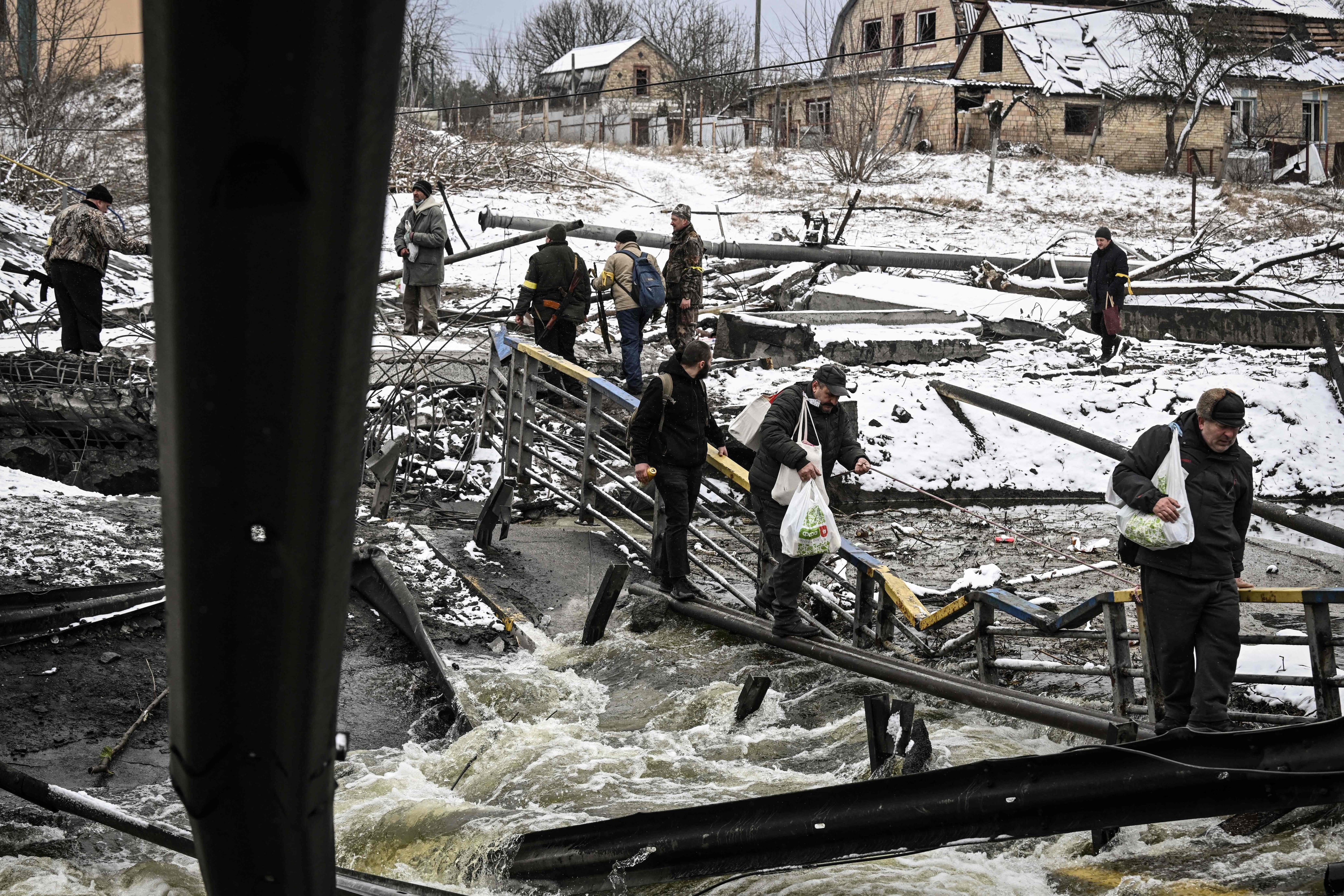 Civilians try to cross a river on a blown up bridge on Kyivs northern front on March 1, 2022. - Defending capital Kyiv, the &quot;key priority&quot; Ukrainian president said. (Photo by ARIS MESSINIS / AFP) (Photo by ARIS MESSINIS/AFP via Getty Images)