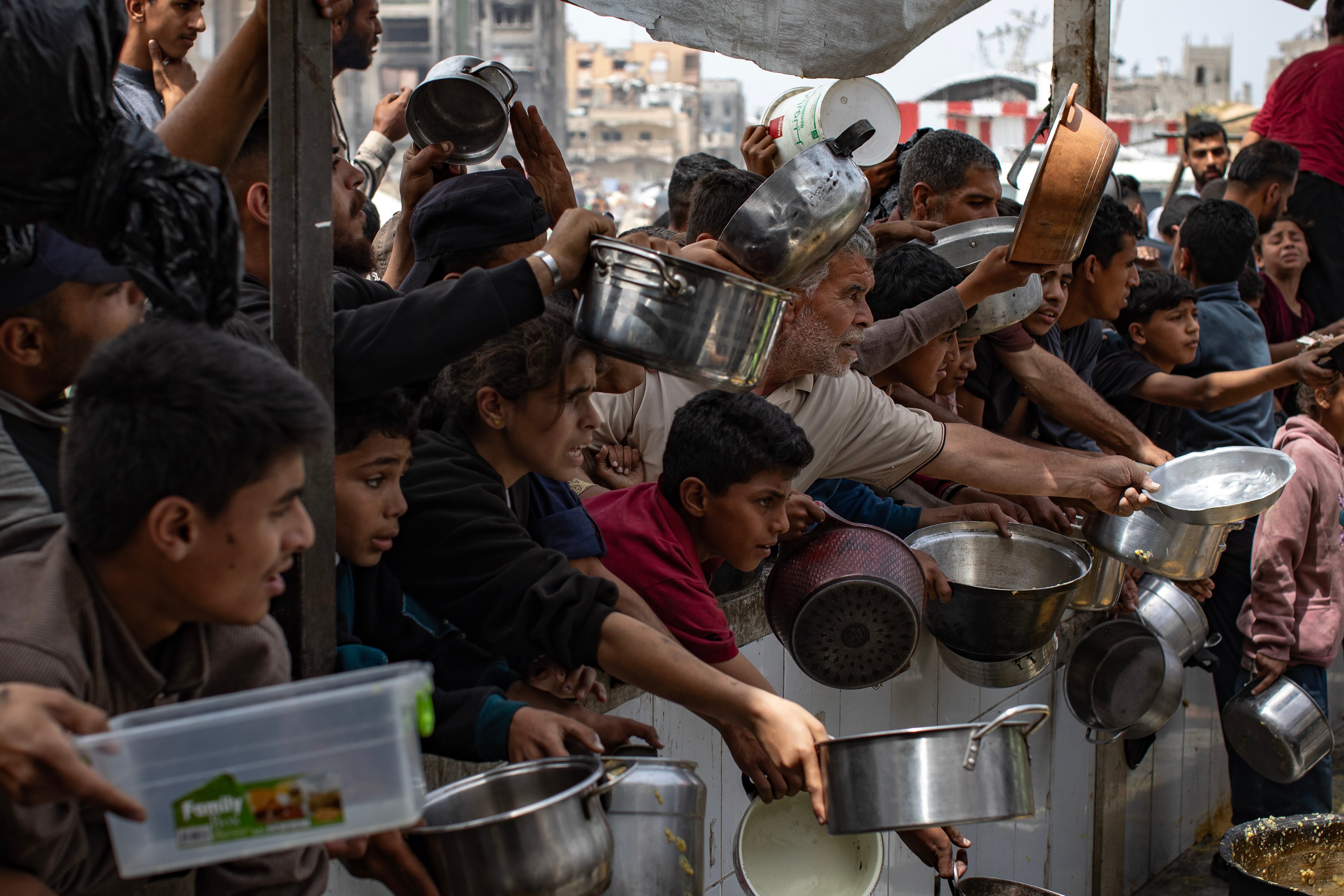 Palestinos desplazados recogen comida donada de la UNRWA en Jabalia