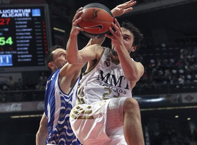 El base del Real Madrid Sergio Llull trata de anotar ante el escolta estadounidense del Lucentum Alicante Andy Rautins durante el partido, correspondiente a la vigésimo novena jornada de la Liga ACB, disputado entre ambos equipos