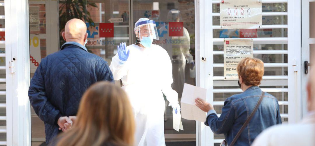 Una sanitaria sale a atender a las numerosas personas que hacen cola en un Centro de Salud madrileño