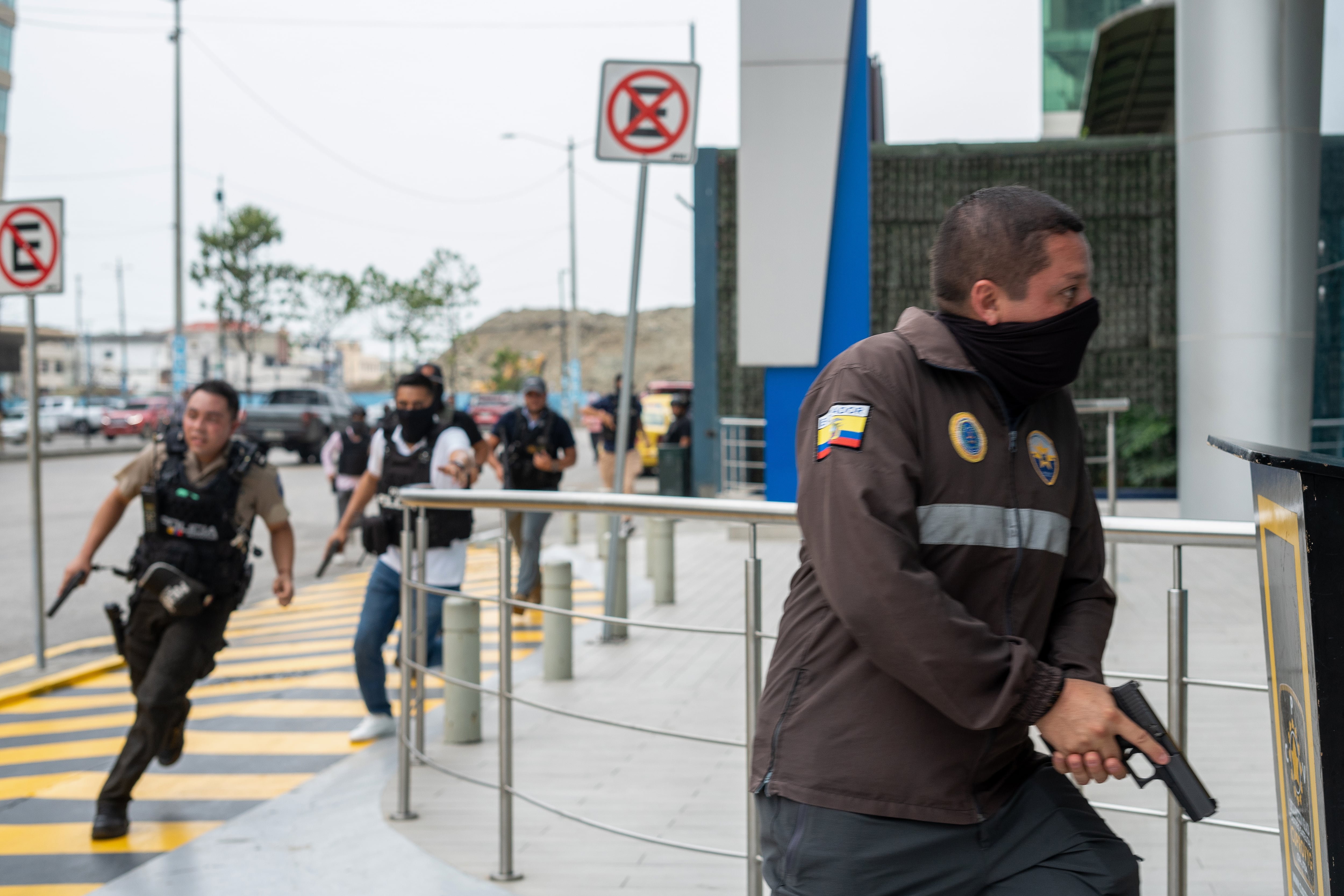 Policías persiguen a un presunto delincuente a pocas cuadras de la sede del canal de televisión TC, donde encapuchados armados ingresaron y sometieron a su personal durante una transmisión en vivo, en Guayaquil (Ecuador).