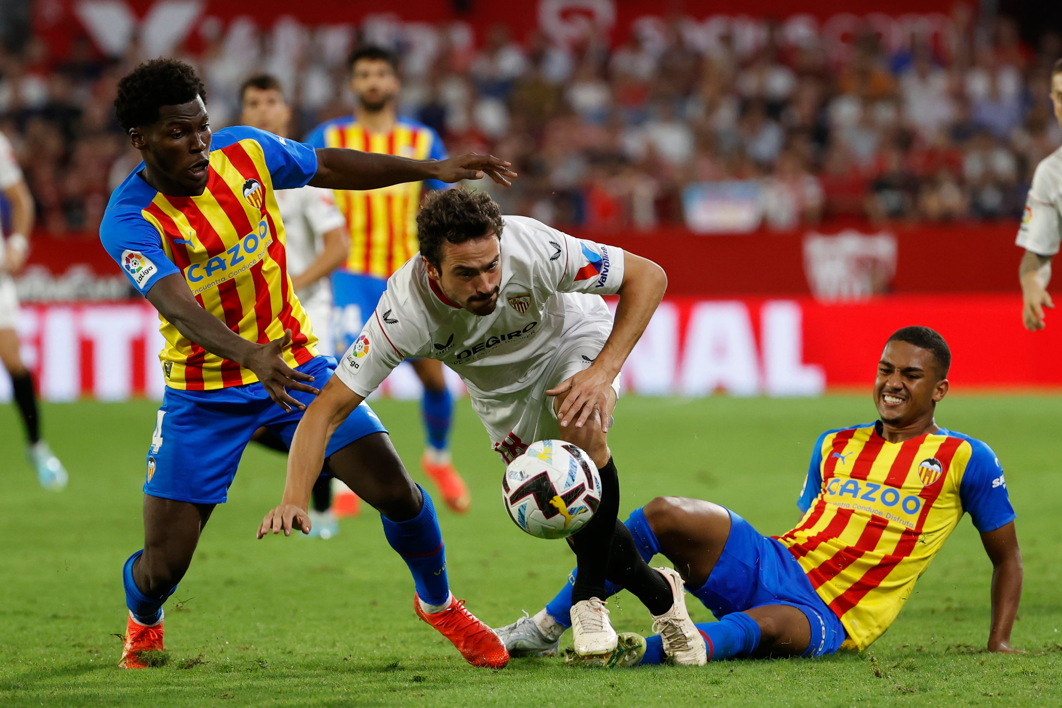 SEVILLA, 18/10/2022.- El centrocampista danés del Sevilla, Thomas Delaney (c), pelea por el balón ante el centrocampista inglés Yunus Musah (i) y el delantero brasileño Samuel Lino (d), ambos del Valencia, durante el partido de la jornada 10 de LaLiga disputado entre el Sevilla FC y el Valencia FC, este martes en el estadio Ramón Sánchez Pizjuán, en Sevilla. EFE/ Julio Muñoz
