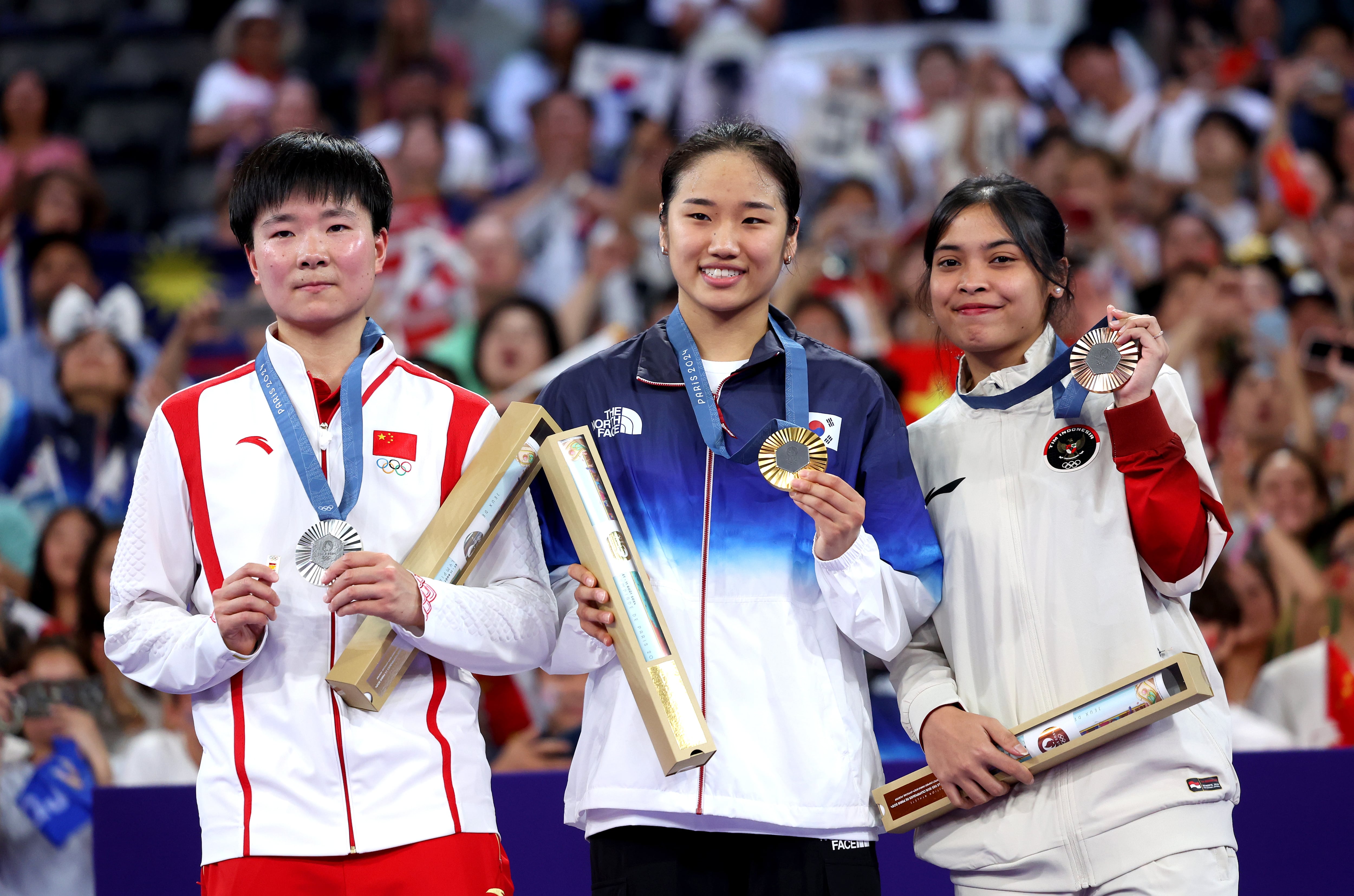 La deportista china He Bing Jiao (izquierda) enseña un pin de España durante el podio de París 2024 de Badminton