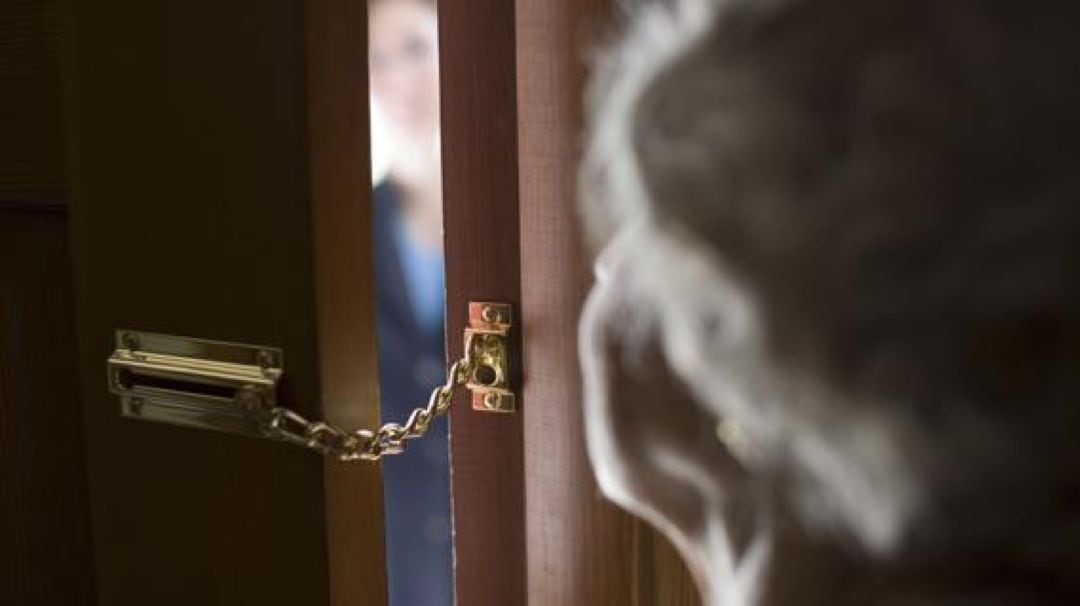 Una mujer jubilada abre la puerta a un individuo