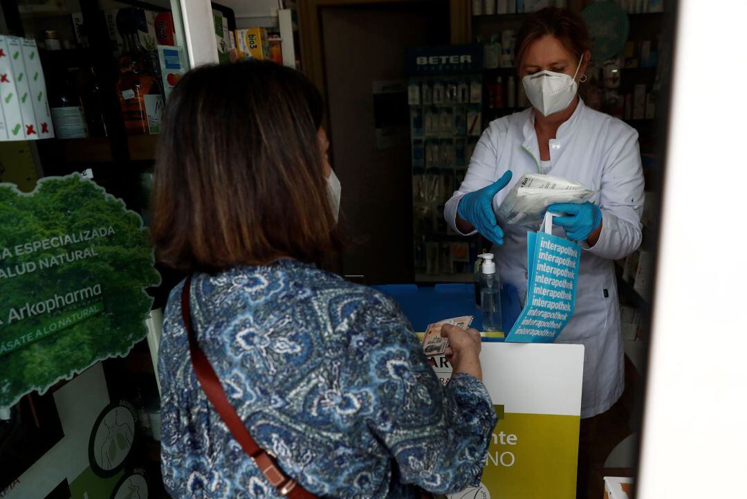 Una mujer recoge en una farmacia la mascarilla que le corresponde del segundo reparto gratuito de otros siete millones de mascarillas en la Comunidad de Madrid que ha comenzado este miércoles