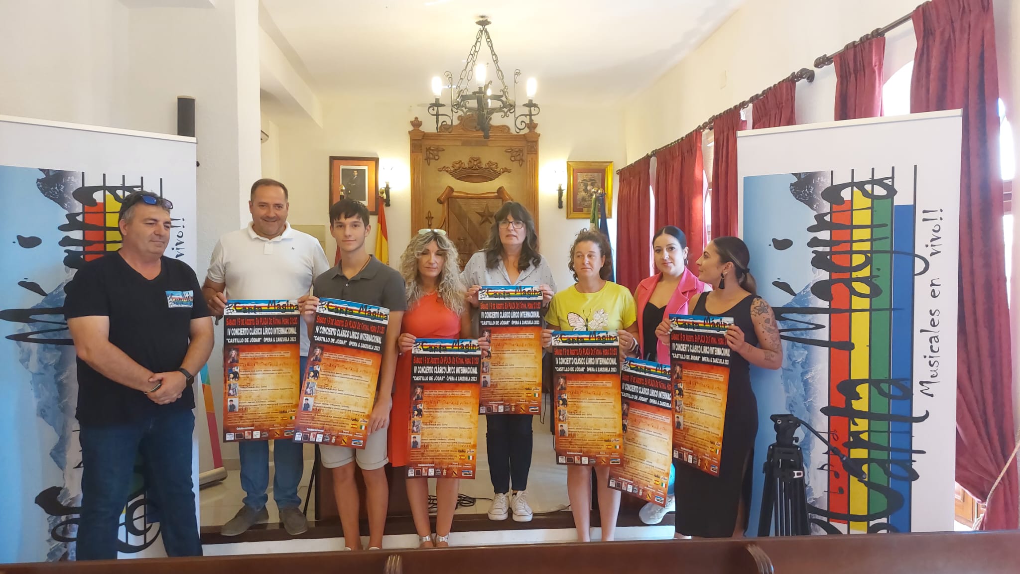 Foto de familia con los participantes en la presentación y concejales, mostrando el cartel anunciador