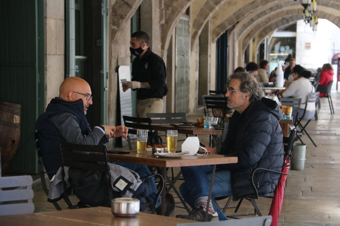 Uns clients prenent una cervesa en una terrassa de la plaça del Vi de Girona