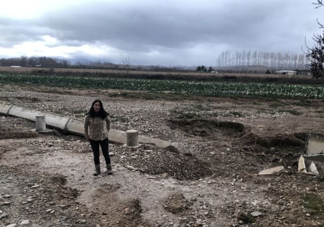 Clara Sarramián junto a los canales de riego que destruyó la crecida del río Ebro. Al fondo, la finca que quedó completamente cubierta por las aguas.