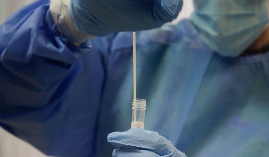 Una trabajadora sanitaria sostiene una probeta con una prueba PCR