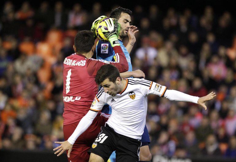 Valencia's goalkeeper Diego Alves (L) catches the ball next to team mate Jose Luis Gaya (front) and Sevilla's Vicente Iborra during their Spanish first division soccer match at the Mestalla stadium in Valencia, January 25, 2015. REUTERS/Heino Kalis (SPAIN - Tags: SPORT SOCCER)