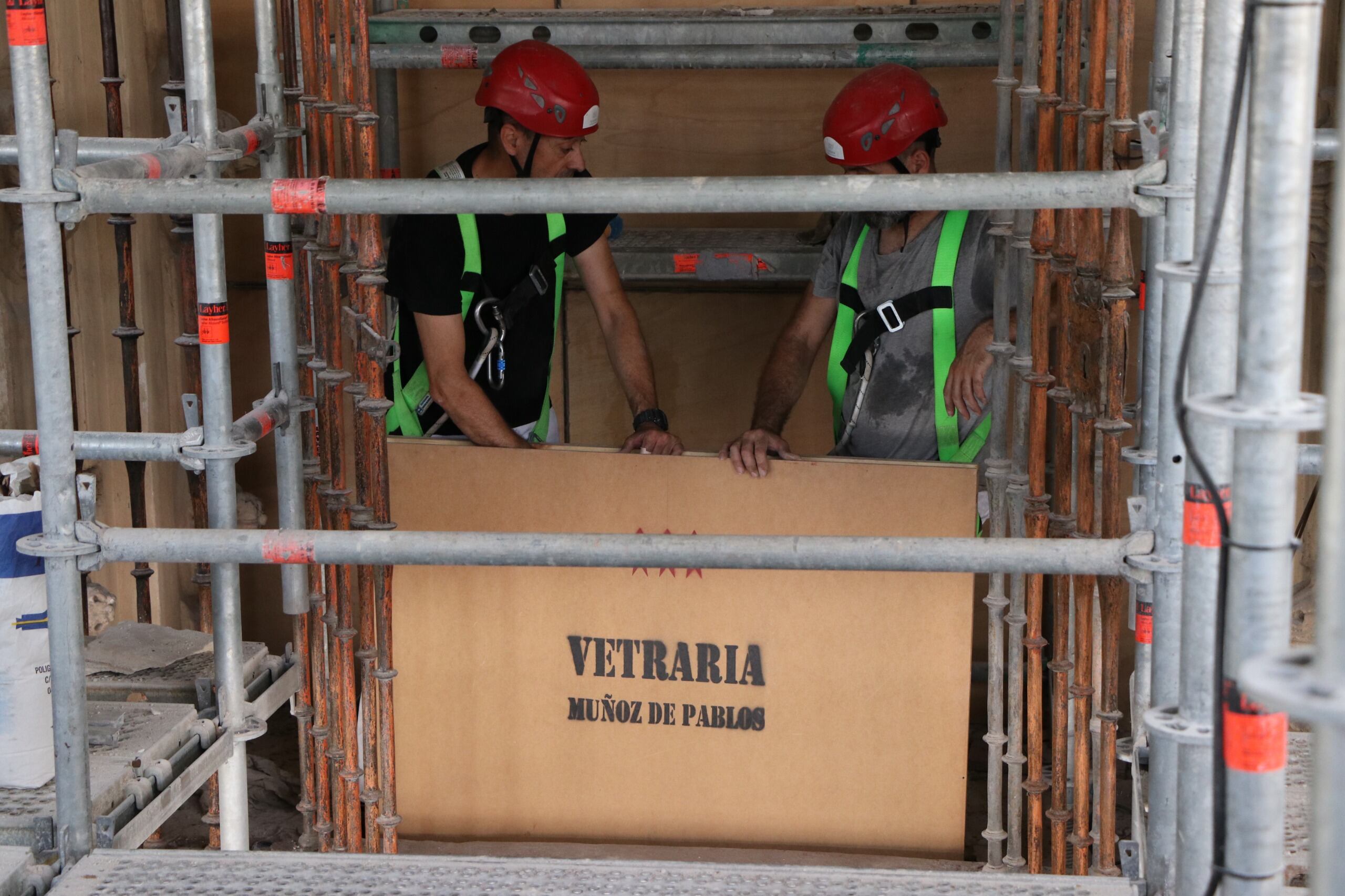 Dos operarios de Vetraria Muñoz de Pablos durante la subida de la vidriera dedicada a la Virgen de la Fuensanta este miércoles.