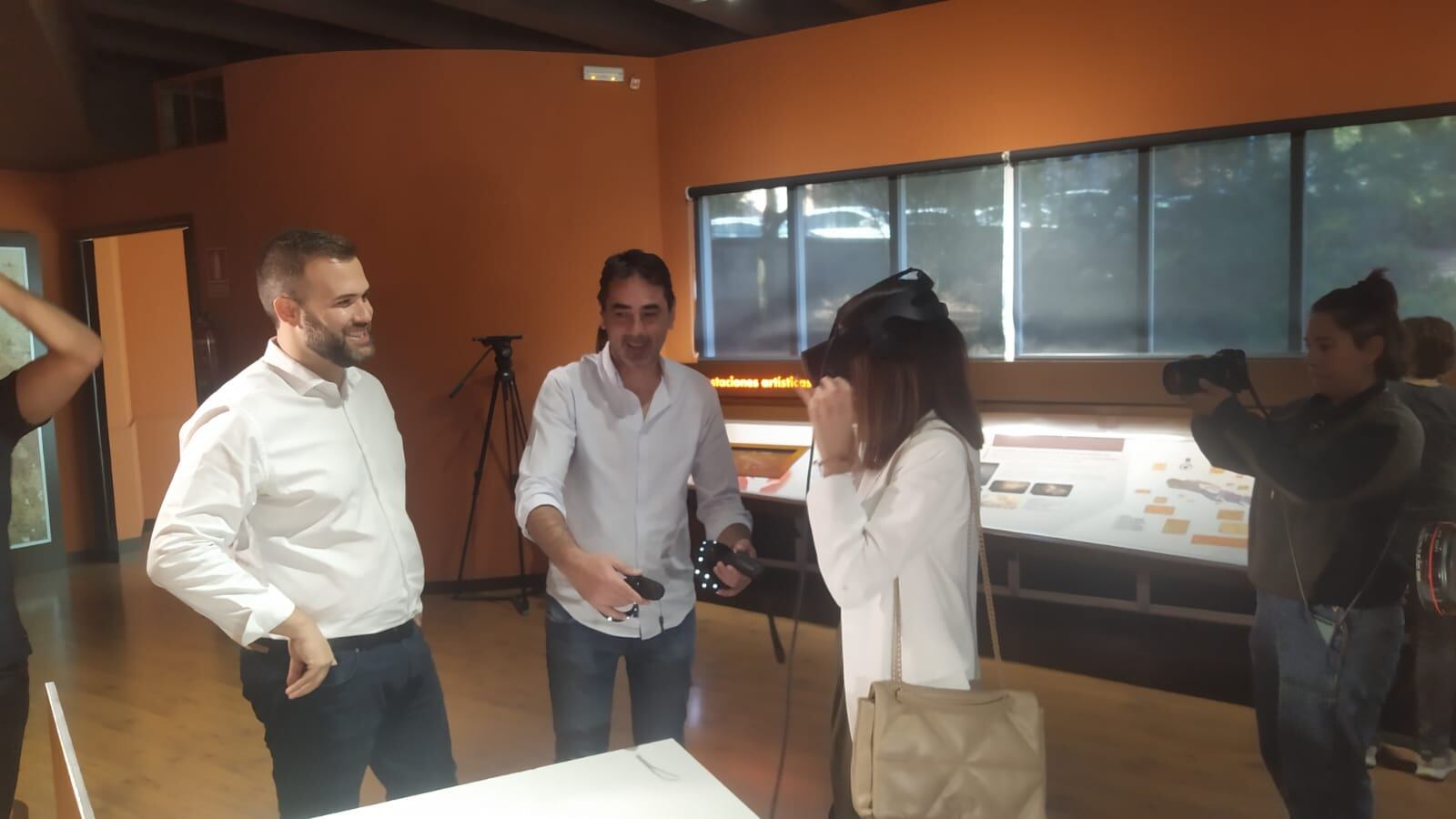 El alcalde de Cáceres (izq), Luis Salaya, observa como la consejera de Cultura (Dcha),  Nuria Flores, se coloca las gafas de realidad virtual de la cueva de Maltravieso