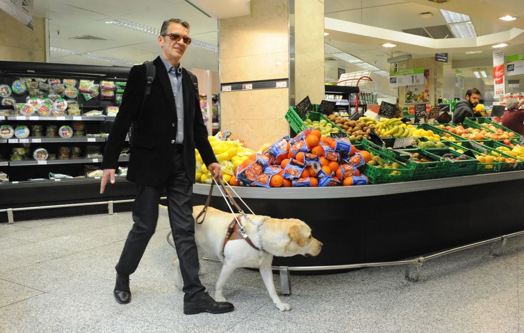 Un invidente camina con su perro guía por un supermercado.