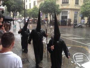 Nazarenos bajo la intensa lluvia caída.