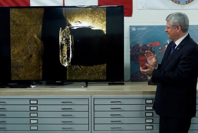 El primer ministro de Canadá, Stephen Harper, aplaude después de revelar una imagen que muestra uno de los dos barcos de la expedición Franklin perdido