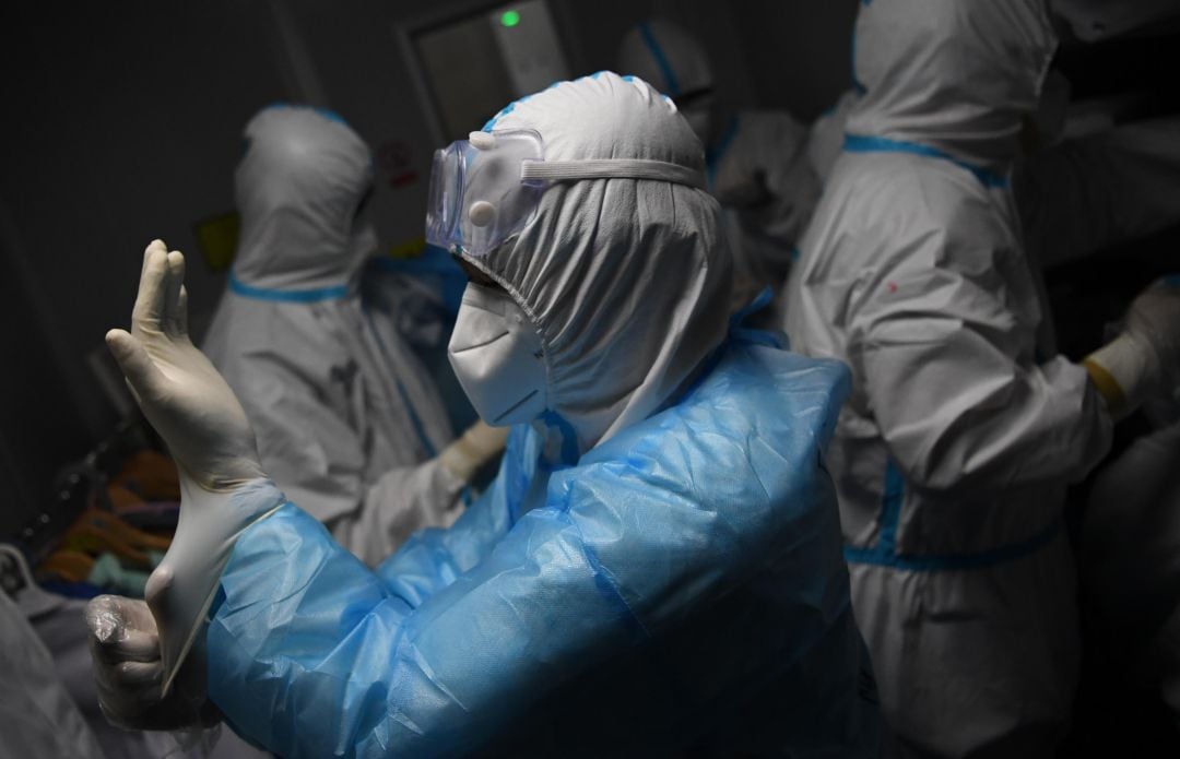 Investigadores chinos se colocan los trajes protectores antes de entrar a trabajar en un laboratorio con muestras de residentes locales.