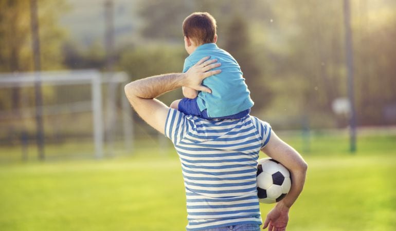 Padre e hijo jugando con un balón de fútbol.