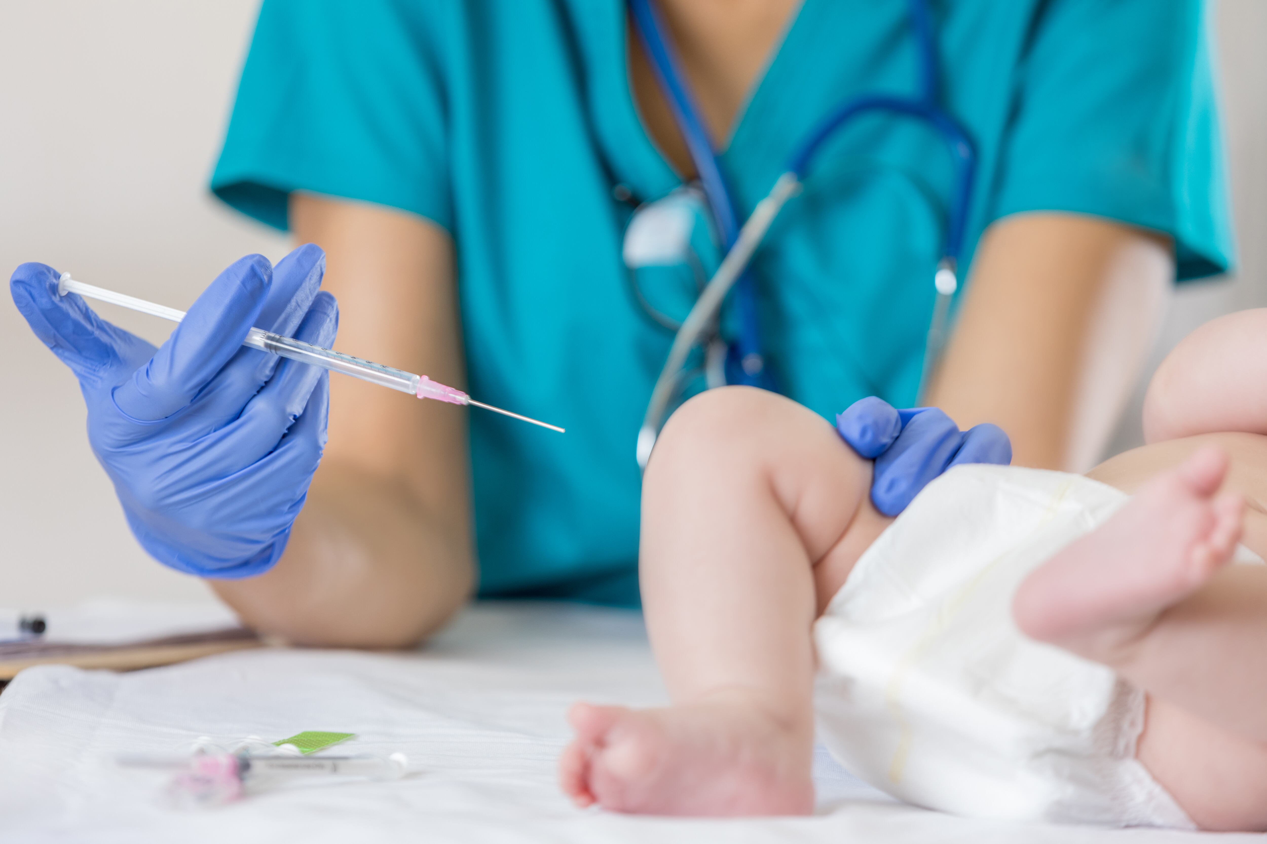 Baby receives immunization from pediatric nurse during well child appointment at pediatrician's office.