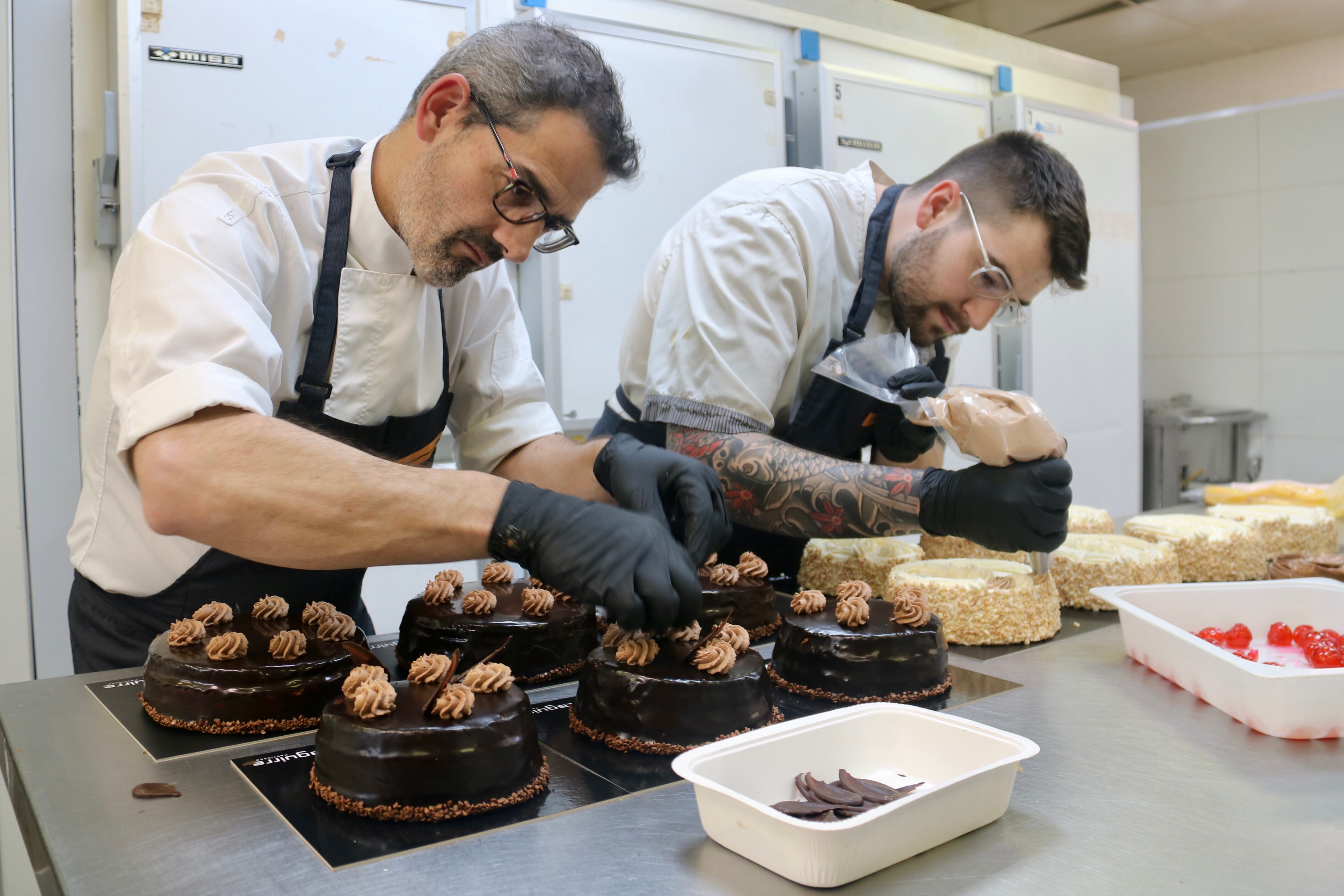Dos pastissers decoren mones a l'obrador de la Pastisseria Zaguirre, a Terrassa
