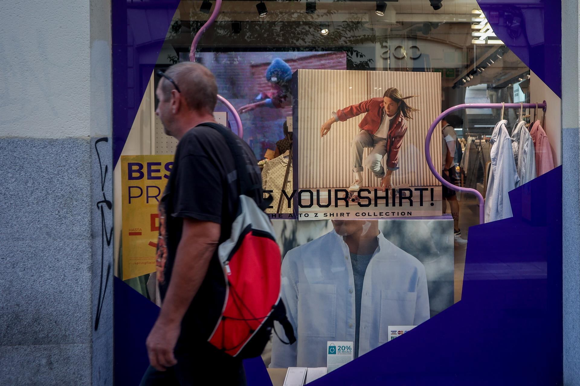 Una persona pasa por delante de un escaparate de una tienda de ropa
