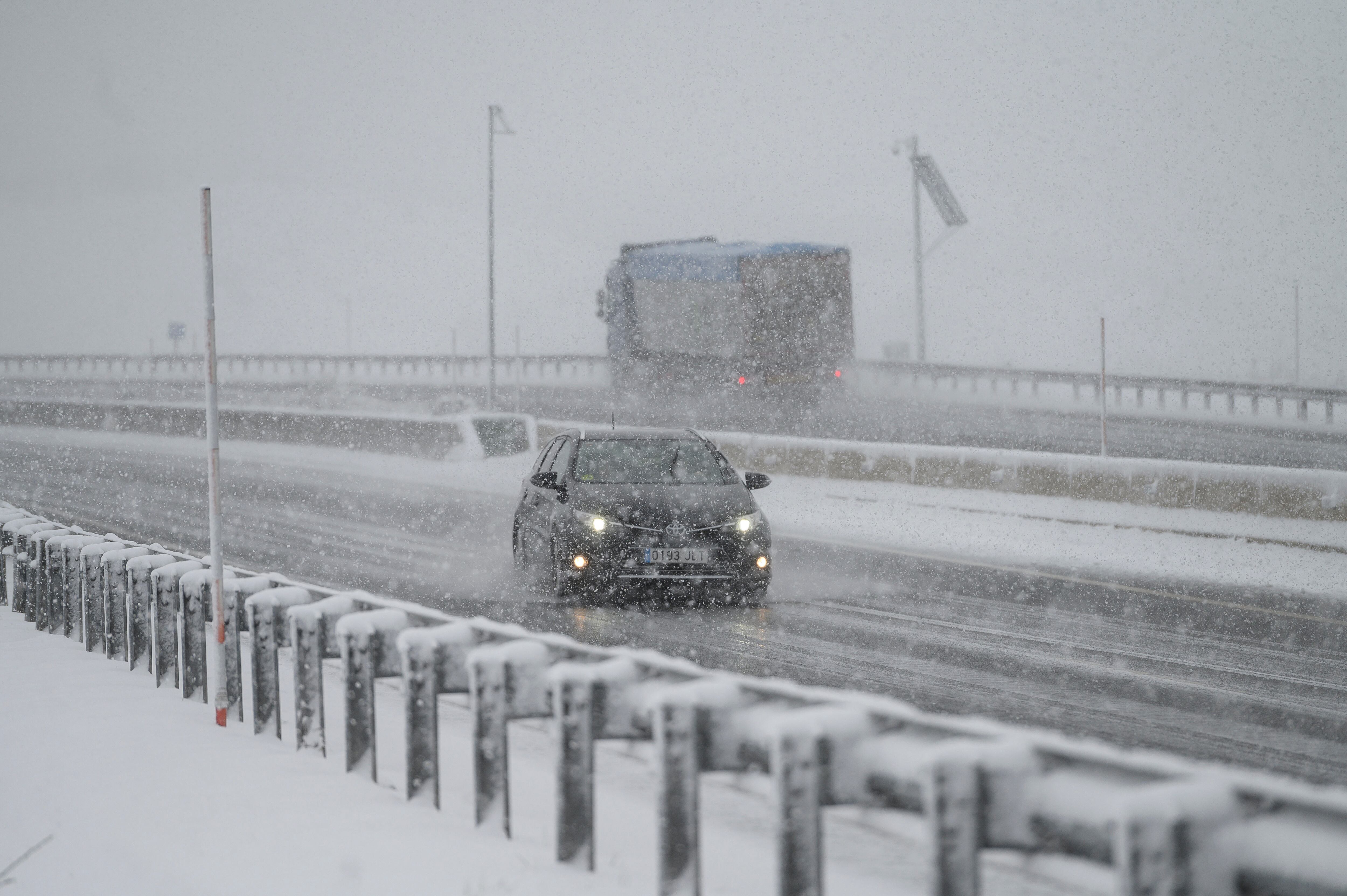 Un vehículo circula bajo la nieve por la autopista A-6