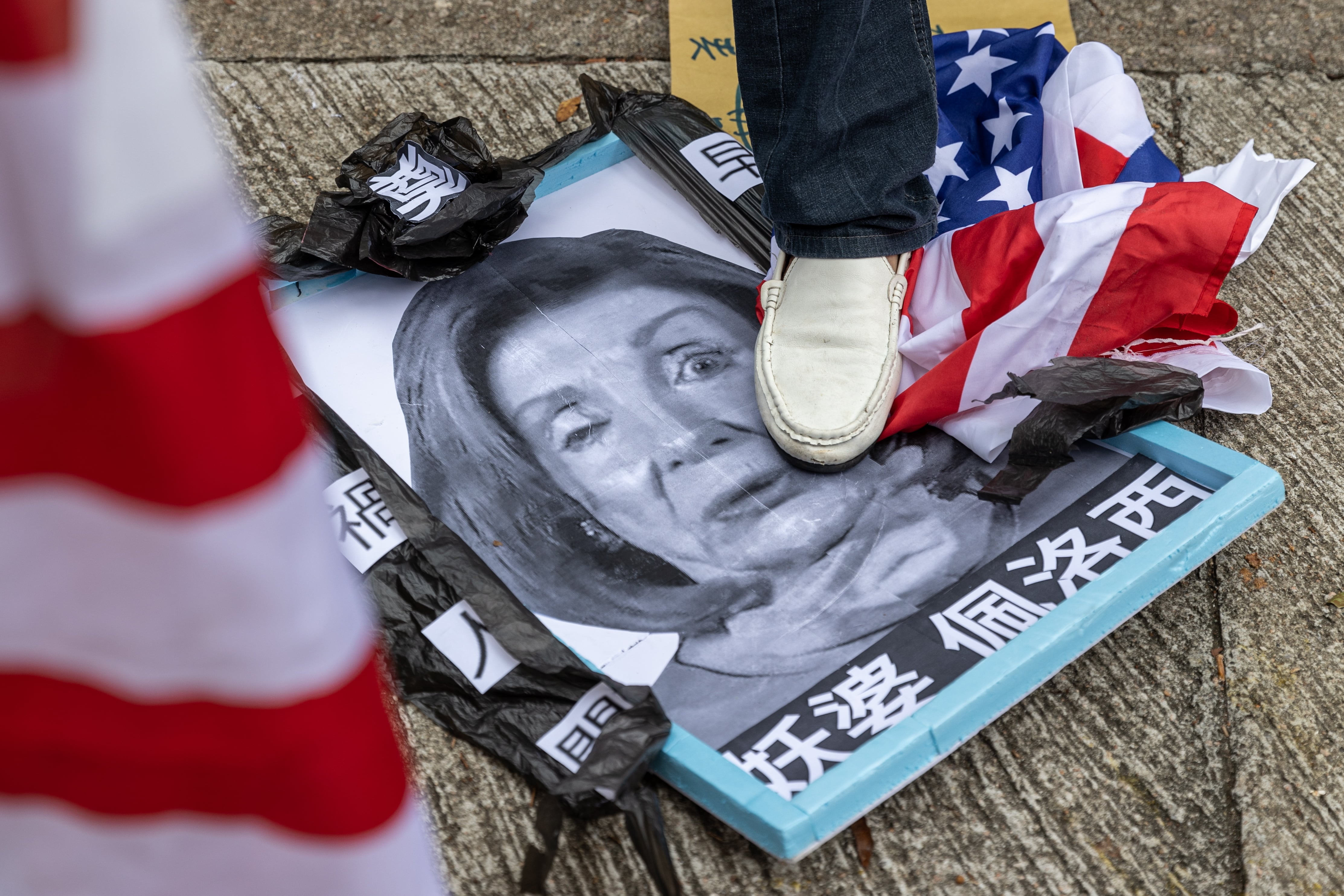 Un grupo de manifestantes pro-China pisa una foto de la presidenta de la Cámara de Representantes de los Estados Unido.