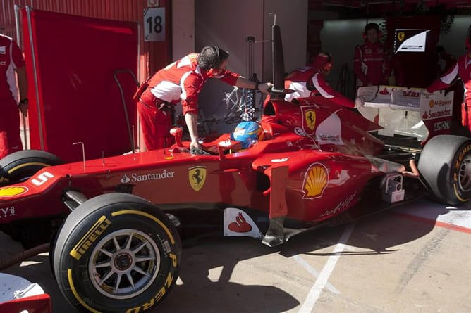 El piloto español de Ferrari Fernando Alonso es ayudado por sus mecánicos durante la segunda jornada de entrenamientos que se realizan en el Circuit de Catalunya, en Montmeló, dentro de los ensayos de los equipos que disputarán el Mundial de Fórmula Uno d