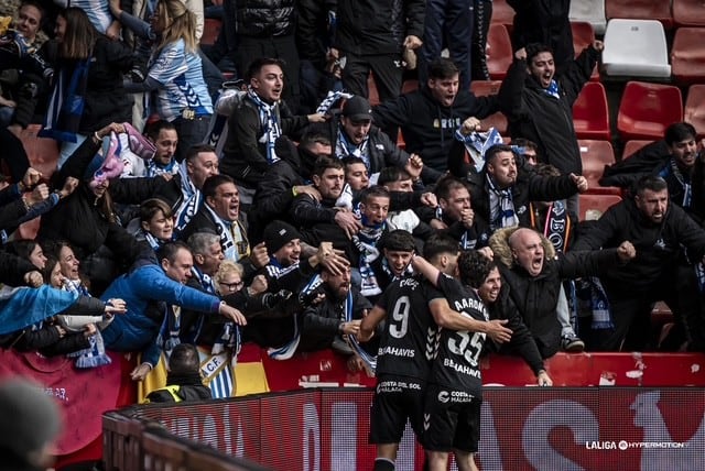 Los jugadores del Málaga celebran unos de los goles con los aficionados malaguistas que presenciaron el partido en directo en el estadio Enrique Castro El Molinón