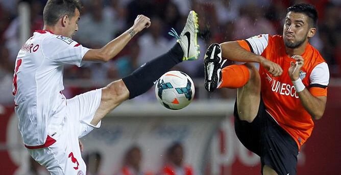 El defensa del Sevilla Fernando Navarro lucha el balón con el chileno Pedro Morales, del Málaga CF, durante un partido de la tercera jornada de Liga en Primera División.