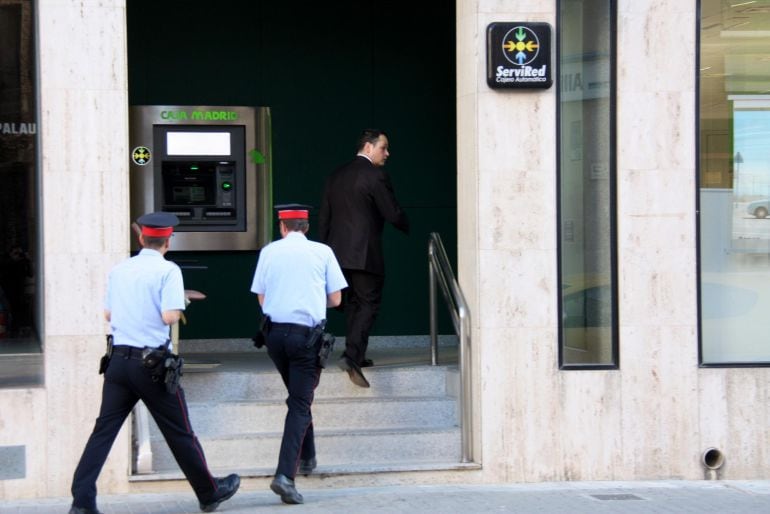 La comitiva judicial, amb el secretari al capdavant acompanyat per dos agents dels Mossos, entra a l'oficina de Caja Madrid (Bankia) a l'Avinguda Alcalde Palau d'Amposta, a finals de maig del passat 2013