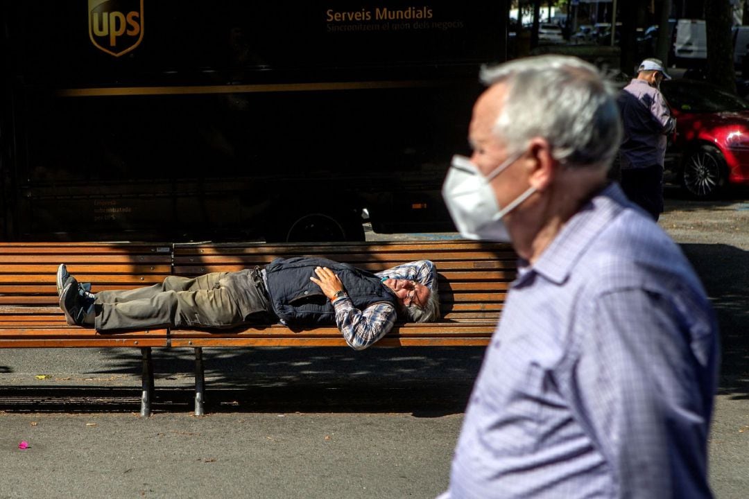 Una persona duerme en un banco de la calle este lunes en Barcelona.