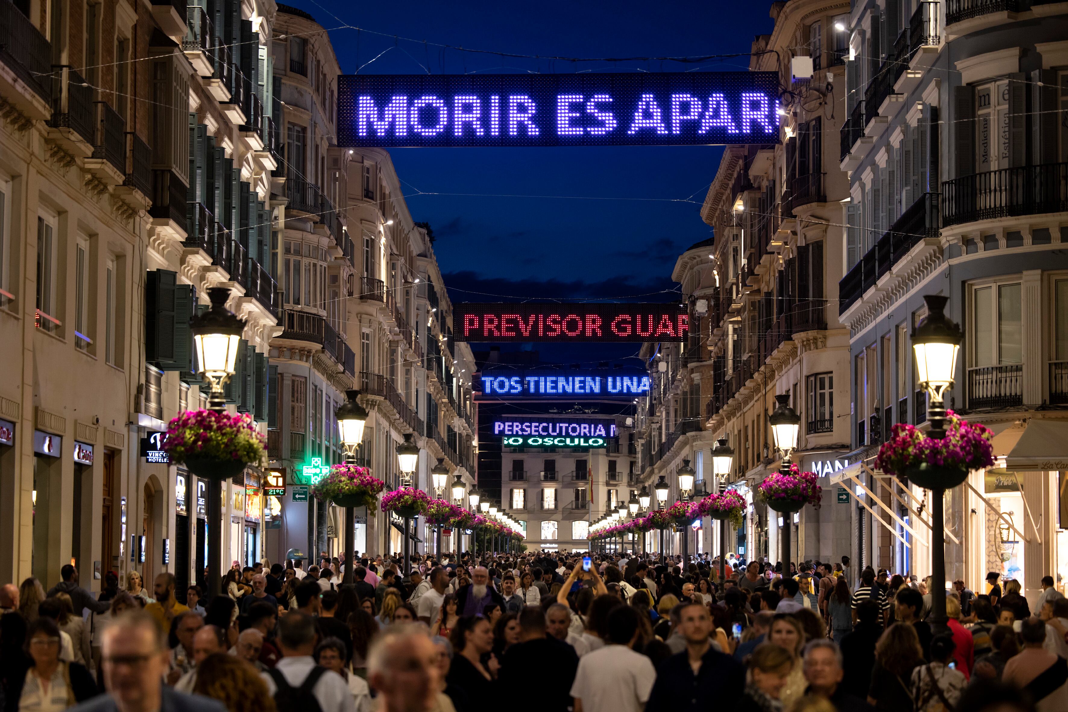 Málaga (España) 10/05/2025.- Numerosas personas recorren la calle Larios del centro de Málaga donde está instalada la intervención artística 'La ley ascendente de la poesía', con las palabras y versos del poeta Rafael Pérez Estrada, durante la Noche en Blanco que se celebra en la ciudad. EFE / Daniel Pérez.