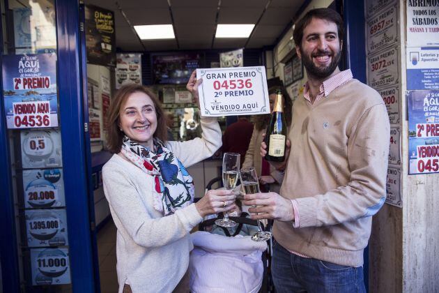 Santiago Garrido, y su madre Amelia Ramos, propietarios de la administración número 1 de Fuengirola (Málaga), brindan con el cartel del segundo premio del Sorteo Extraordinario de la Lotería de Navidad, el 04.536, del que han vendido 52 décimos muy repart