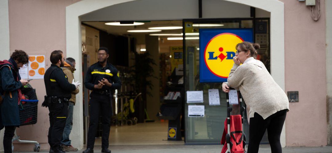 Una mujer espera con su carro de la compra a poder entrar a un supermercado Lidl