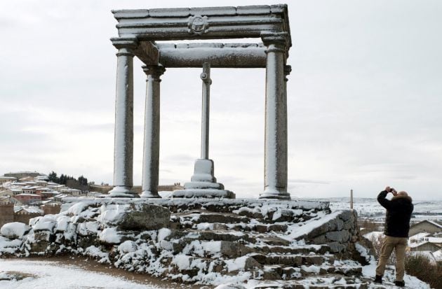 Un hombre toma una fotografía de los Cuatro Postes con la nieve caída durante la madrugada en Ávila.