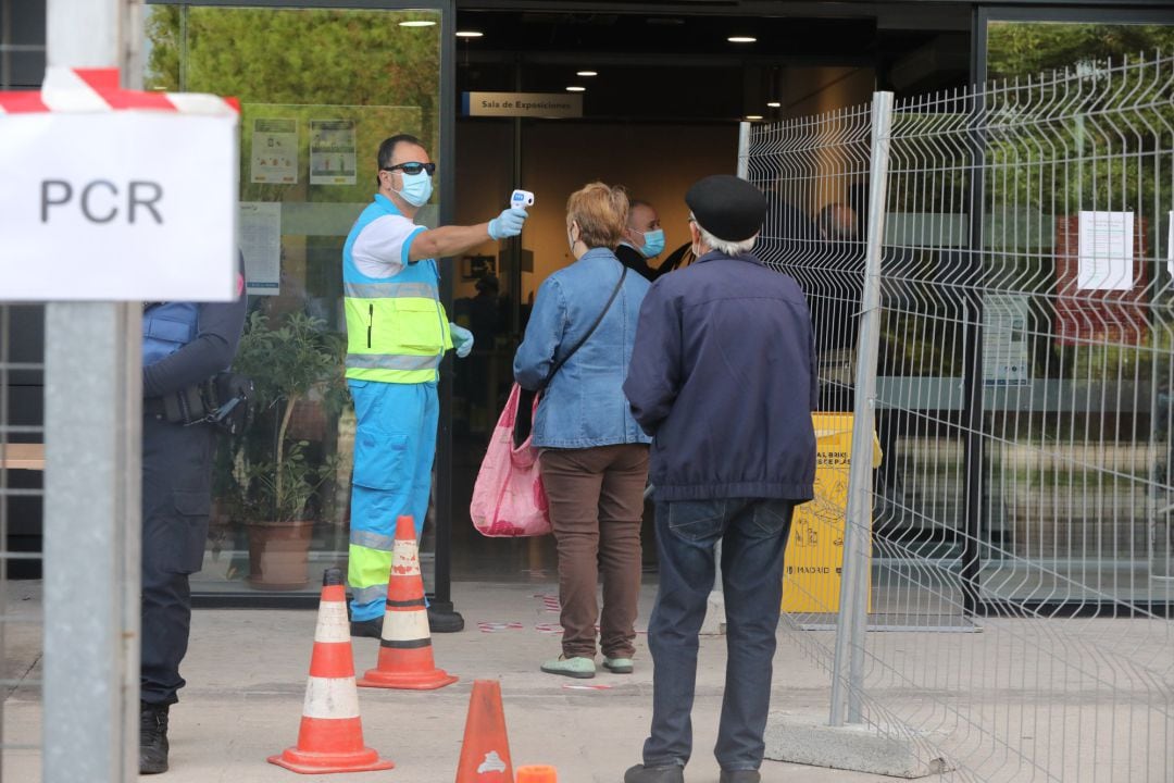 Un trabajador toma la temperatura a los vecinos antes de entrar al Centro Cultural Lope de Vega.