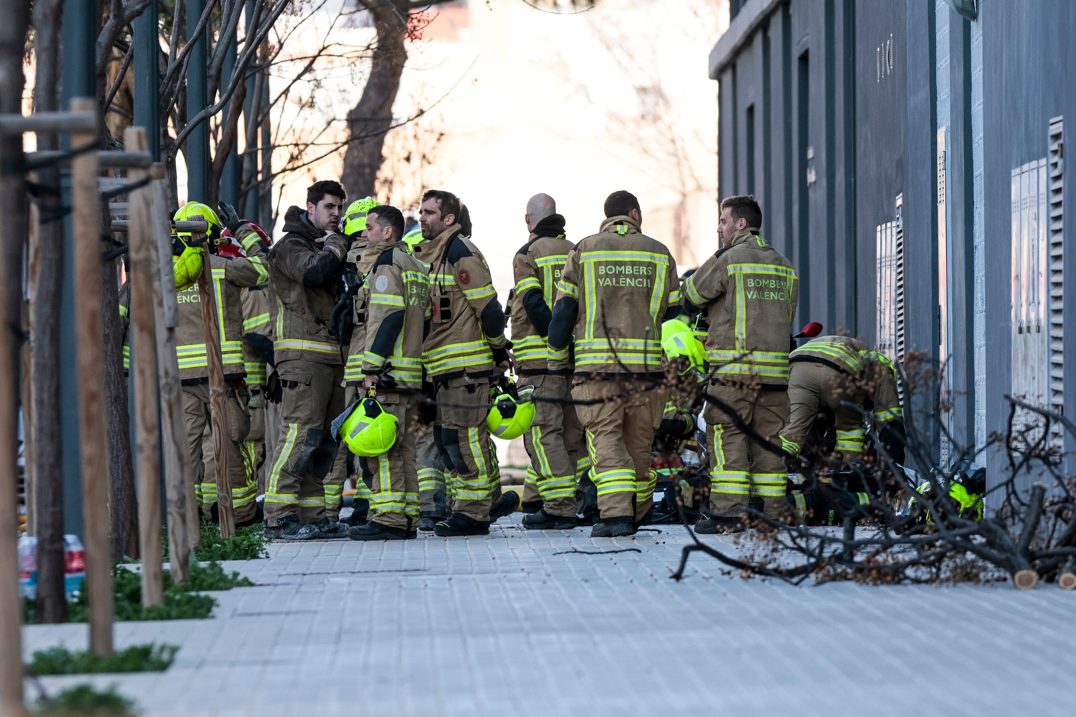 GRAFCVA8590. VALENCIA, 23/02/2024.- El juzgado de guardia eleva a cinco el número de muertos por el incendio de un edificio en el barrio de Campanar de València. En la imagne un grupo de bomberos espera en los alrededores del edificio incendiado, mientras continúan los esfuerzos para tratar de localizar a las posibles víctimas. EFE/Biel Aliño
