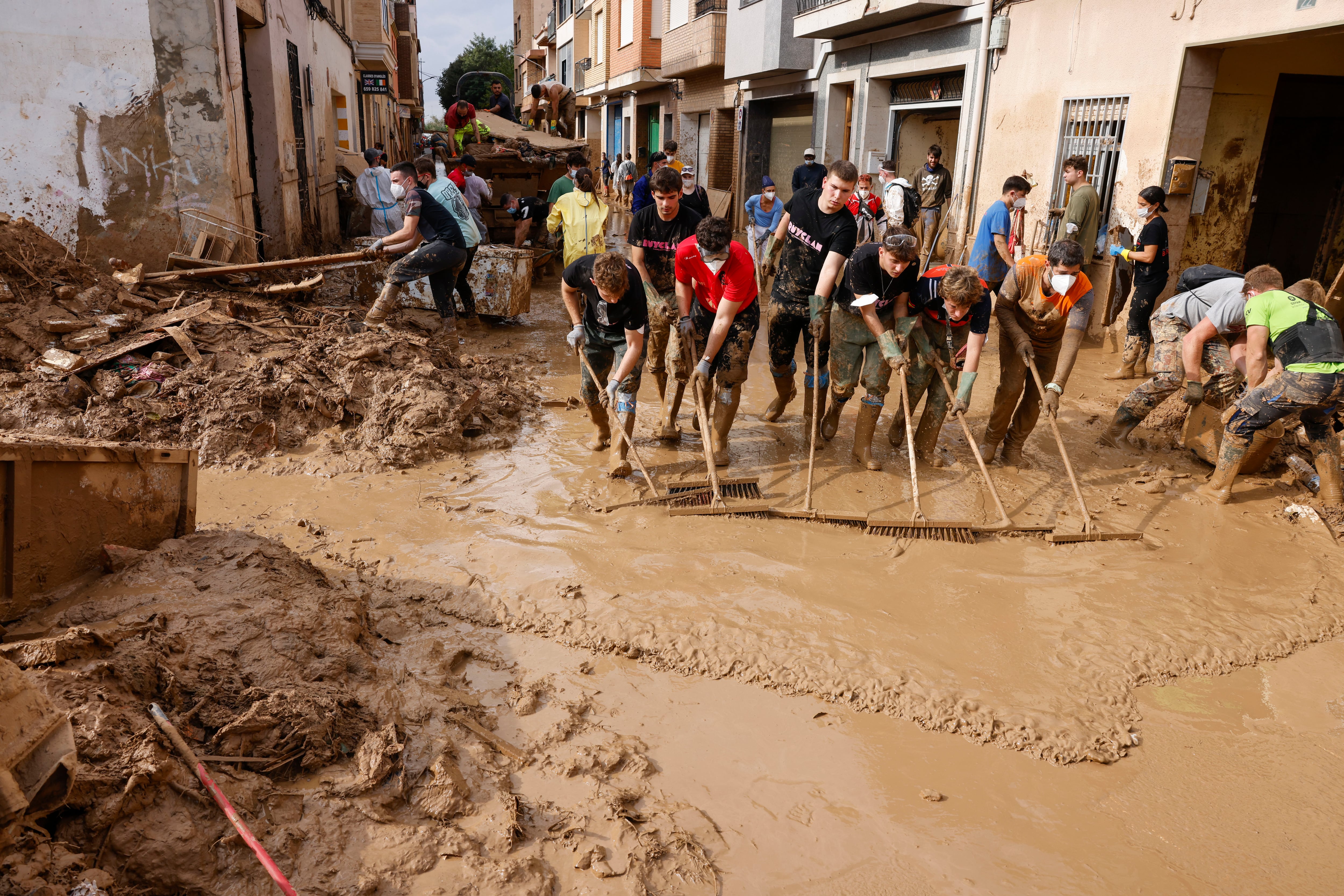 MASANASA (VALENCIA), 07/11/2024.-  Voluntarios barren el lodo de una calle de Masanasa, Valencia.