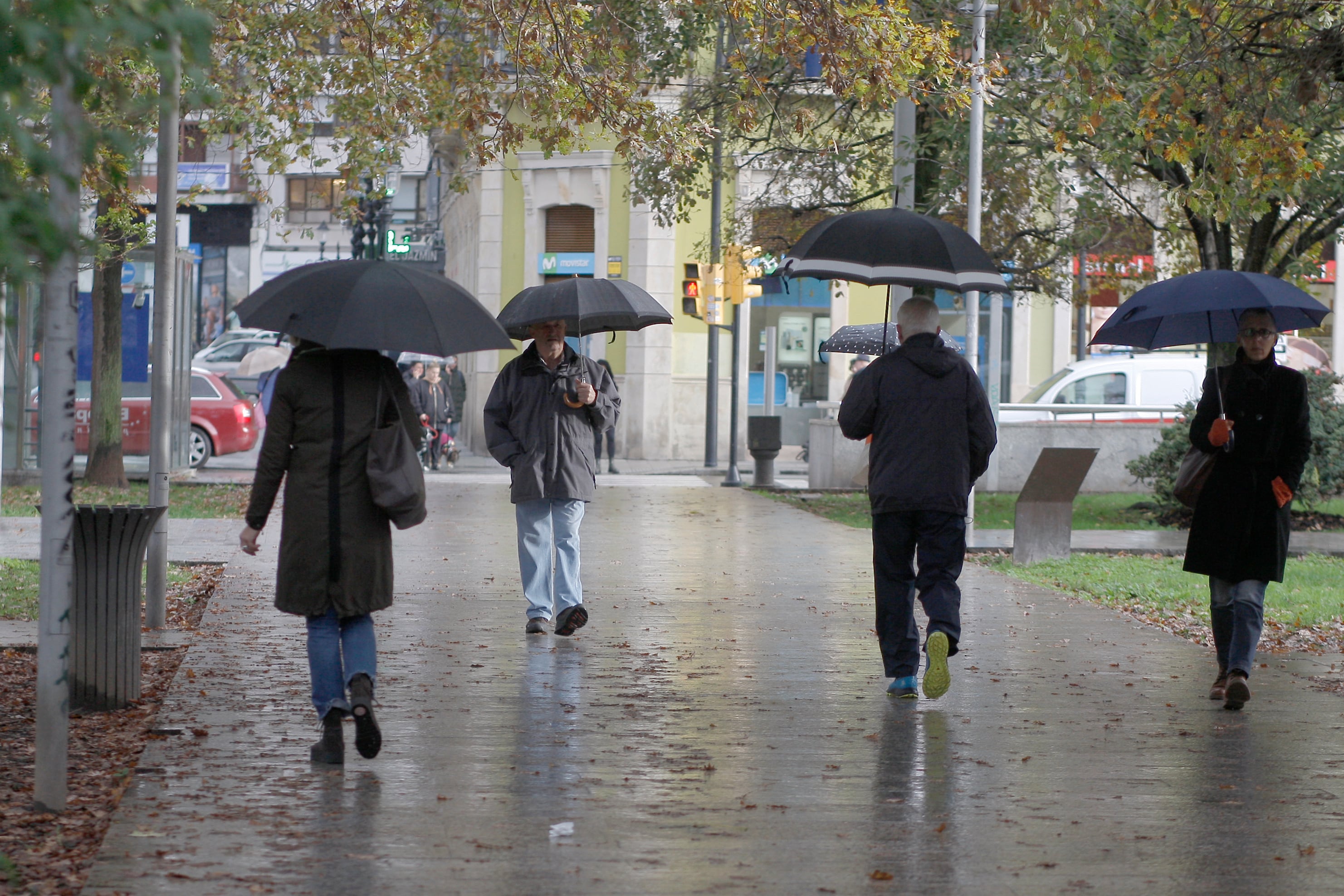 Un grupo de personas caminan bajo la lluvia en la Plaza de Europa de Gijón