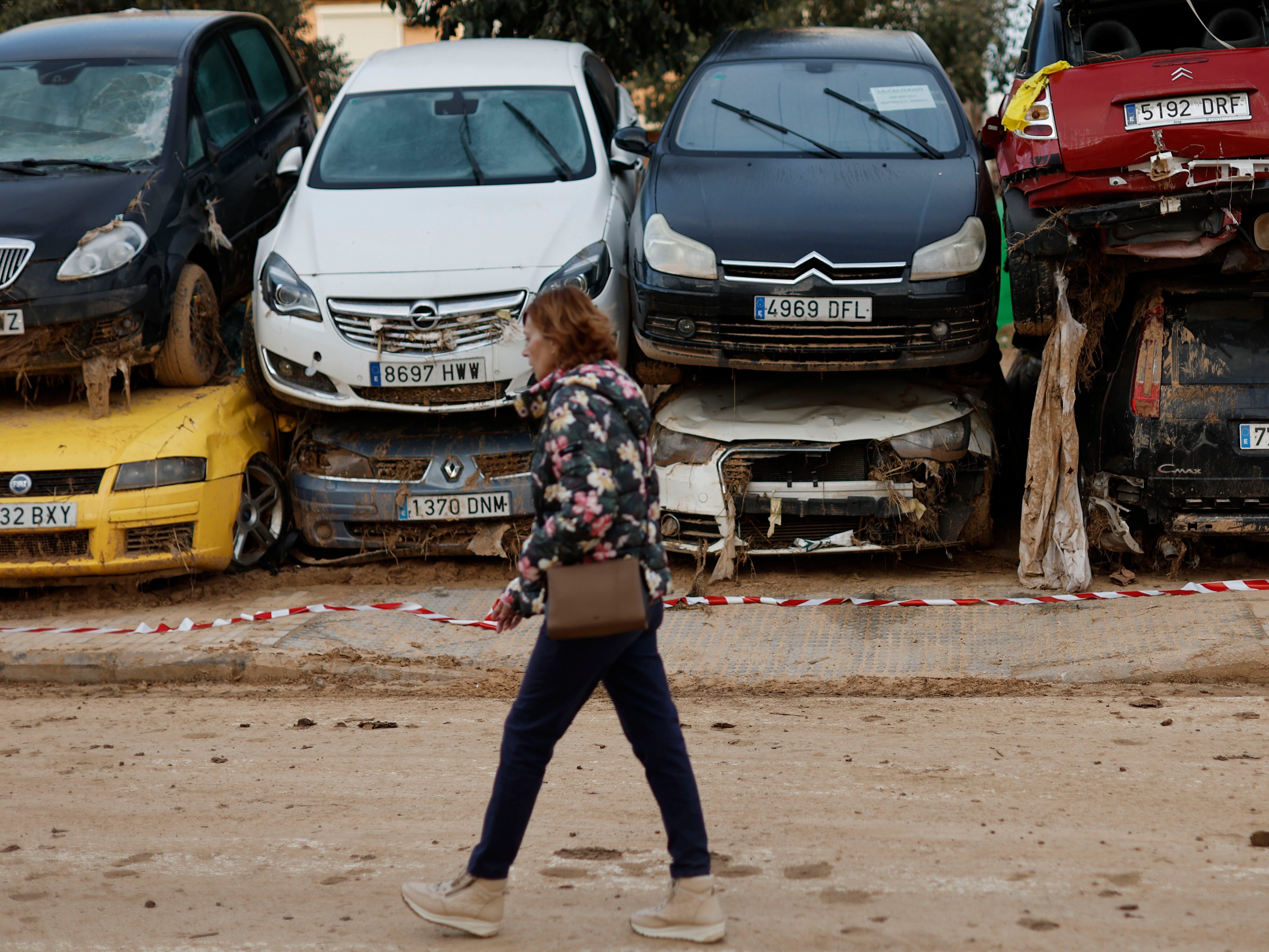 Una mujer pasa junto a decenas de coches que esperan ser retirados en Paiporta