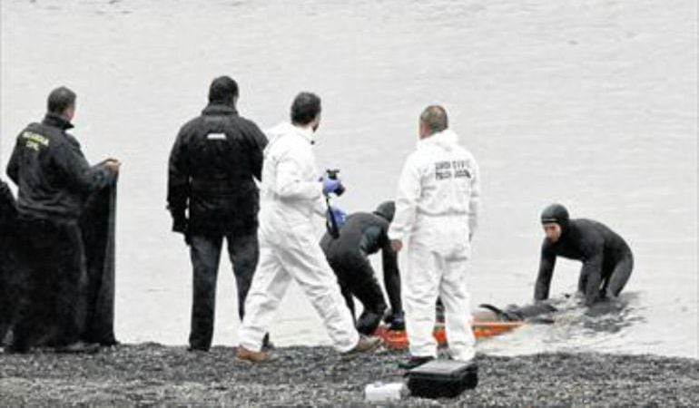 Agentes de la Guardia Civil recogen uno de los cadáveres aparecidos en la playa del Tarajal.