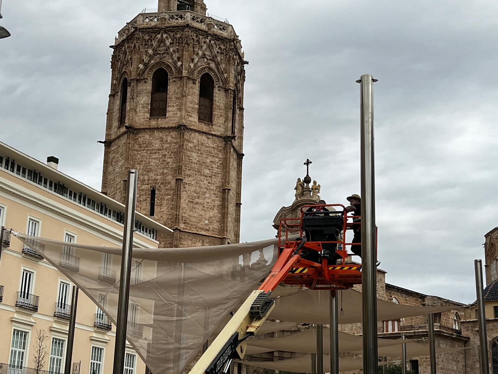 Los técnicos municipales colocan de nuevo los toldos de protección solar en la plaza de la Reina de València.