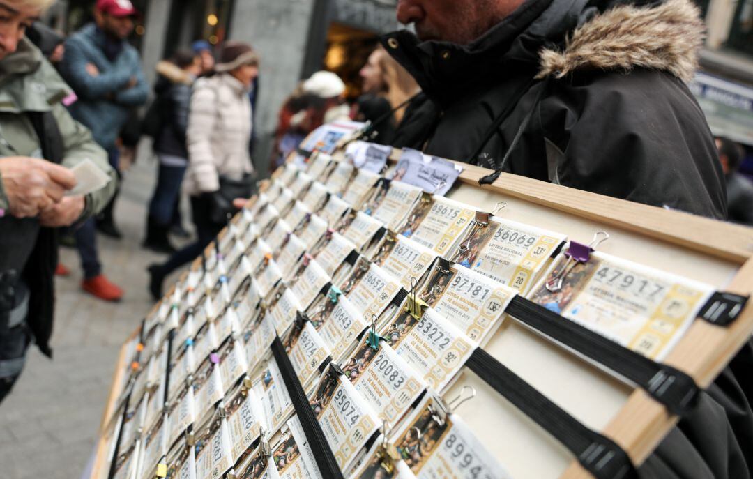 Un hombre vende décimos de Lotería de Navidad de la Administración de Doña Manolita, en Madrid